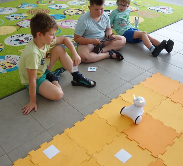 trzech chłopców steruje przy użyciu tabletów robotami Photon