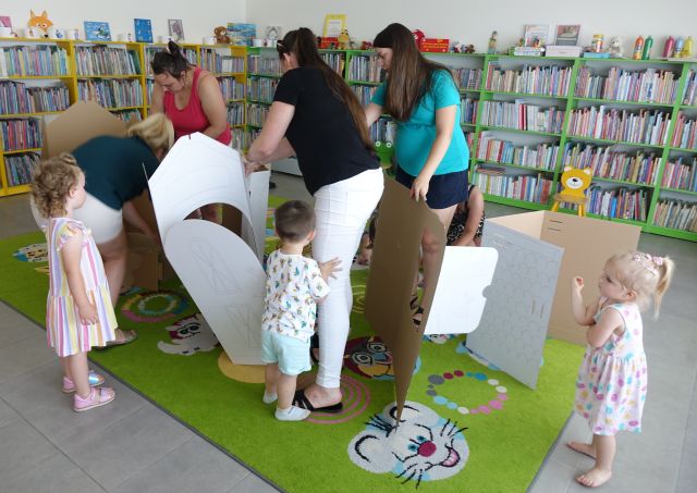 mamy z dziećmi składają domek z tektury
