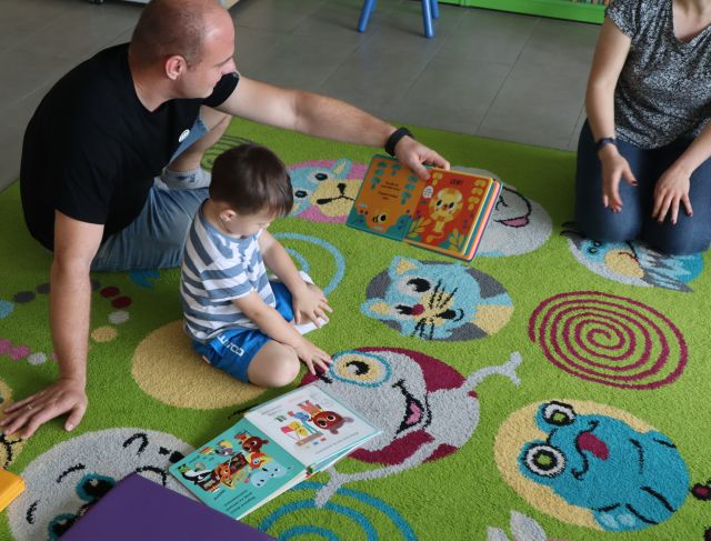 chłopiec z tatą siedzący na dywanie oglądają książki
