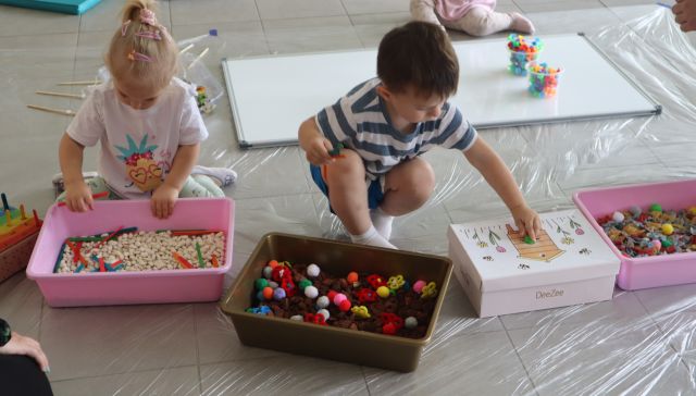 małę dzieci bawią się siedząc na podłodze