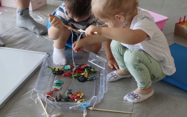małe dzieci wyławiają zabawkowe rybki z miski