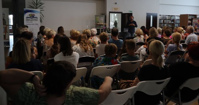 licznie zgomadzona publiczność, przed nimi autor z mikrofonem 