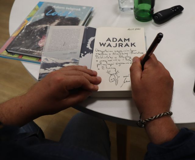 dłonie wpisujące się do książki