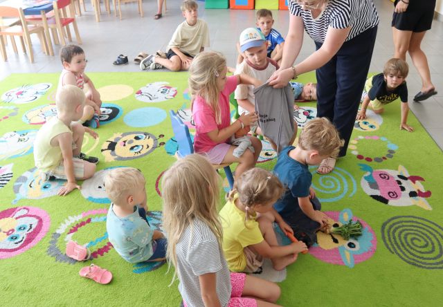 przedszkolaki siedzą na dywanie i losują fanty z worka