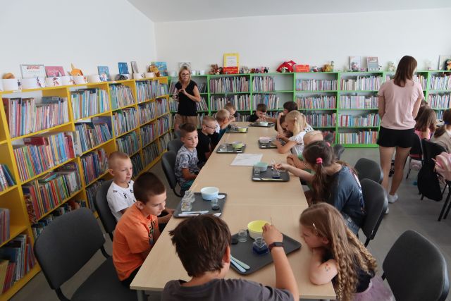 dzieci siedzące przy stolikach mieszają płyny w słoiczkach