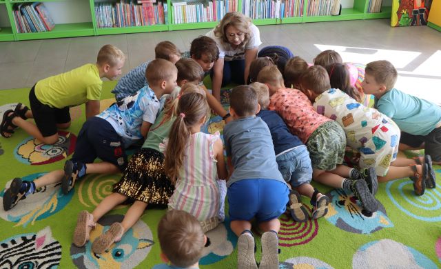 dzieci klęczą w kółeczku i oglądają mapę