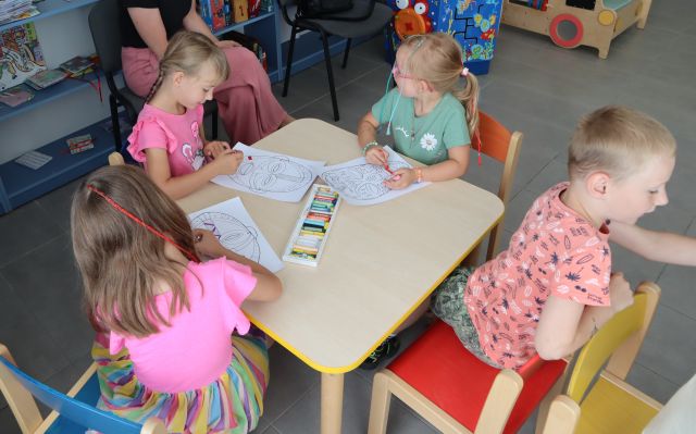 4 dzieci maluje siedząc przy stoliku