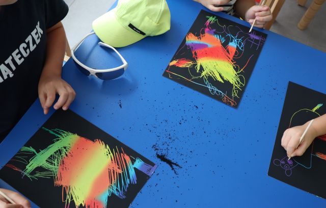 dziecina czarnych kartkach wydrapują rysunki