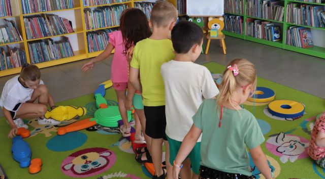 dzieci chodzą po ścieżce sensorycznej, w tle regały z książkami