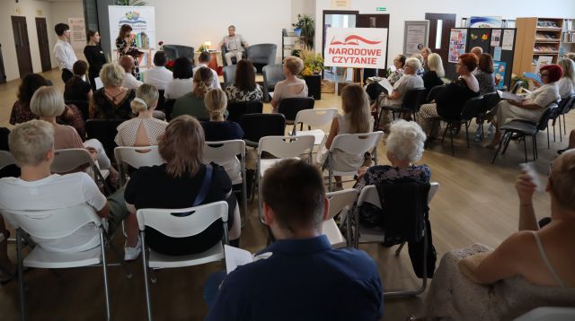 na zdjęciu uczestnicy uroczystości, w tle na scenie czytający teksty