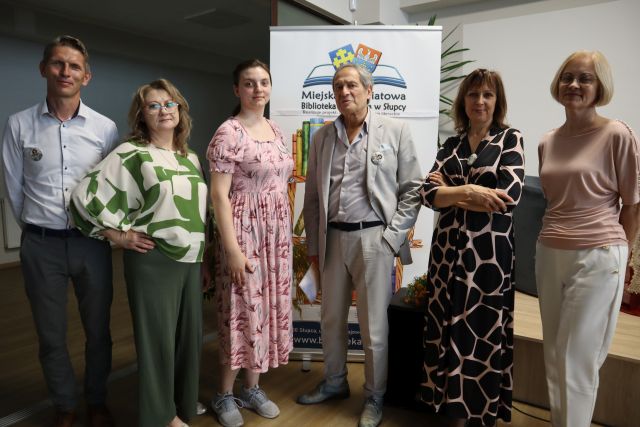 3 bibliotekarki, dyrektorka biblioteki i burmistrz pozują do zdjęcia z aktorem