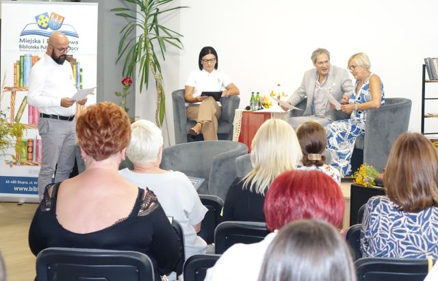 siedzący uczestnicy uroczystości, w tle na scenie lektorzy