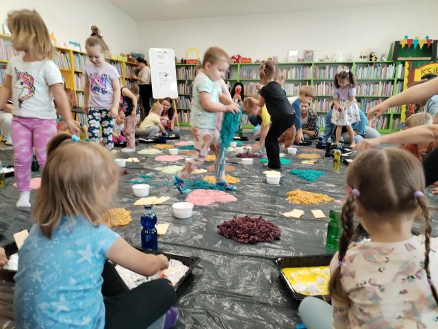 dzieci spacerujące pośród różnych sensorycznych artykułów, w tle regały z książkami