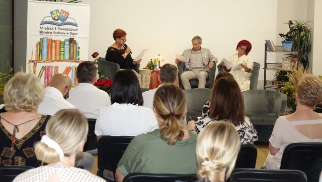 na zdjęciu uczestnicy uroczystości, w tle na scenie czytający