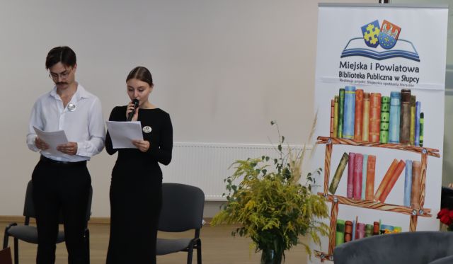 dziewczyna i chłopak prowadzący spotkanie, z prawej strony baner biblioteki