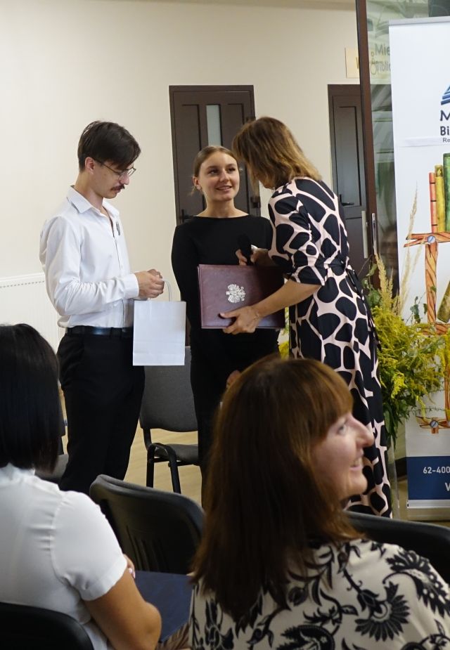 dyrektorka biblioteki wręcza dziewczynie i chłopakowi prezenty