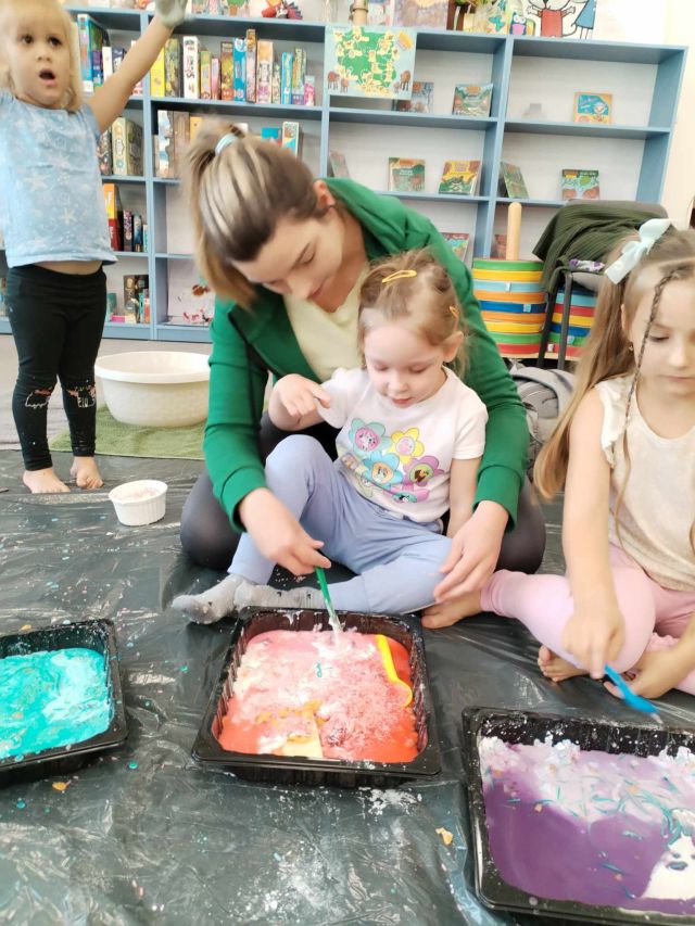 dzieci z rodzicami mieszają kolorowe masy w tackach