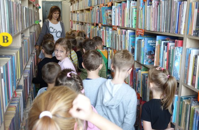dzieci i dyrektorka biblioteki pomiędzy regałami z książkami