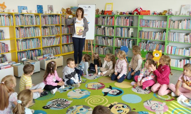 dyrektorka biblioteki pokazuje dzieciom kartę biblioteczną