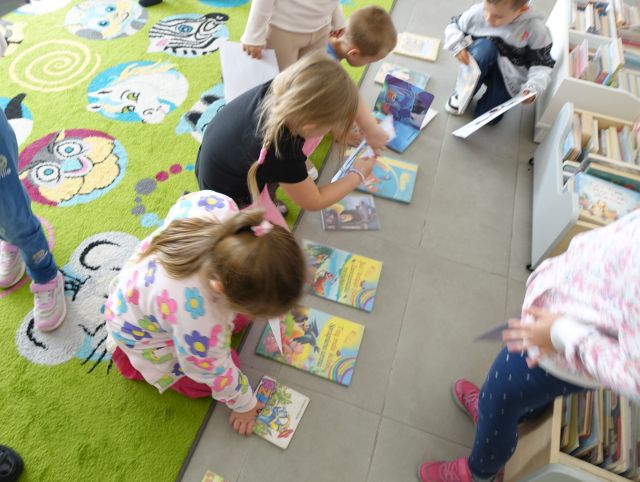 dzieci oglądaja ułożone na podłodze książki