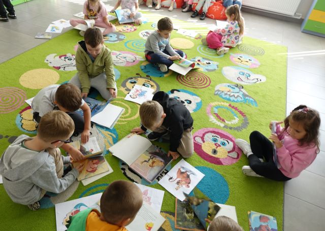 dzieci na dywanie przeglądają ksiązki