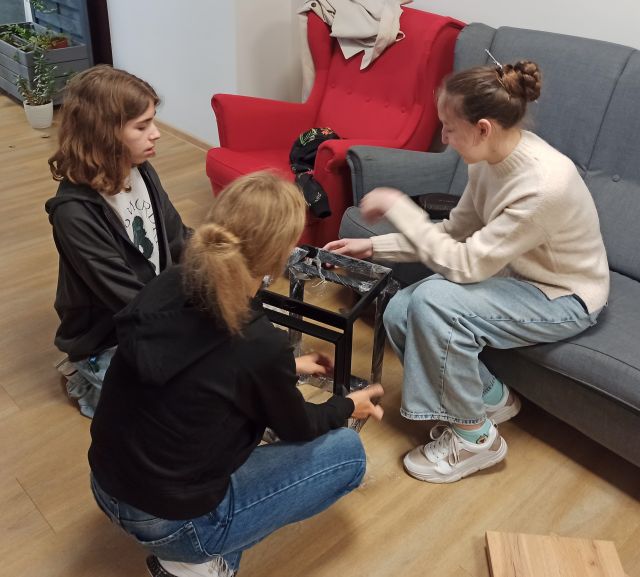 3 dziewczyny i chłopak składają taboret