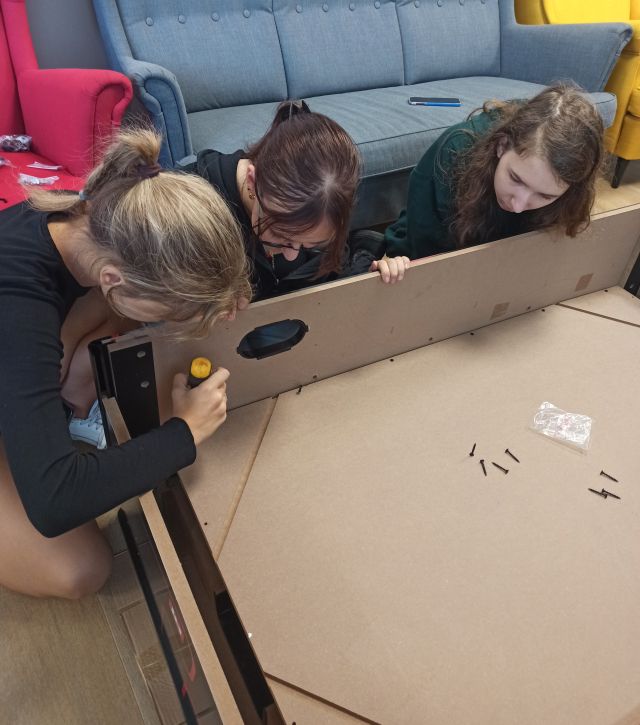 dziewczyna skręca skrzynie, 2 jej pomagają