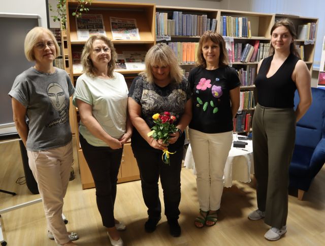 dyrektorka i 4 bibliotekarki pozują do zdjęcia z autorką, w tle regały z książkami