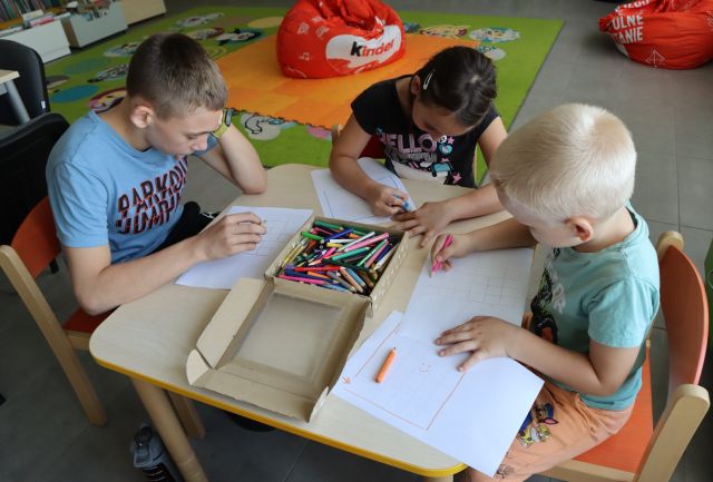 3 dzieci przy stoiku rysują labirynty