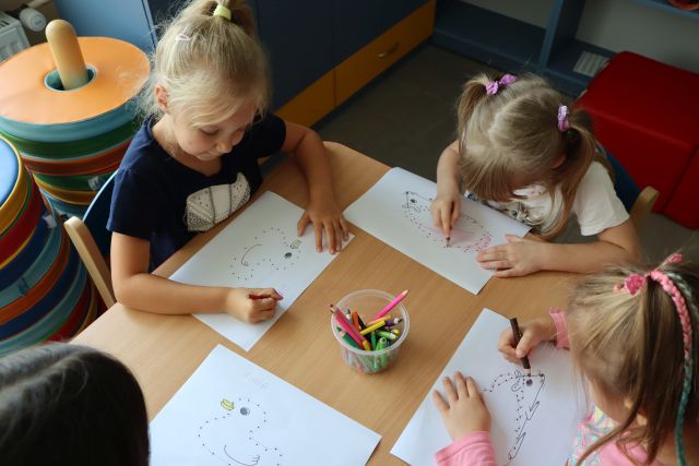 dzieci siedząc przy stoliku łączą kropki