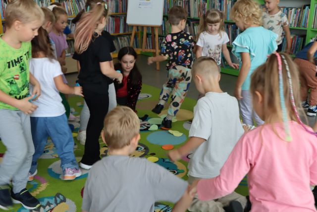 dzieci biegają z kropkami po kolorowym dywanie