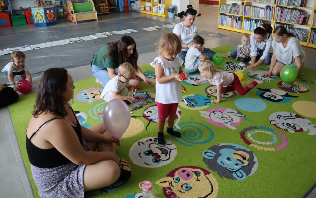 dzieci i rodzice bawią się balonami na kolorowym dywanie