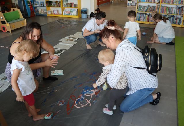 dzieci i rodzice malują na folii balonami wypełnionymi wodą umaczanymi w farbach