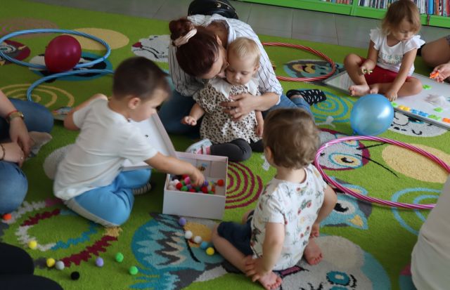 dzieci z mamami bawią się na kolorowym dywanie