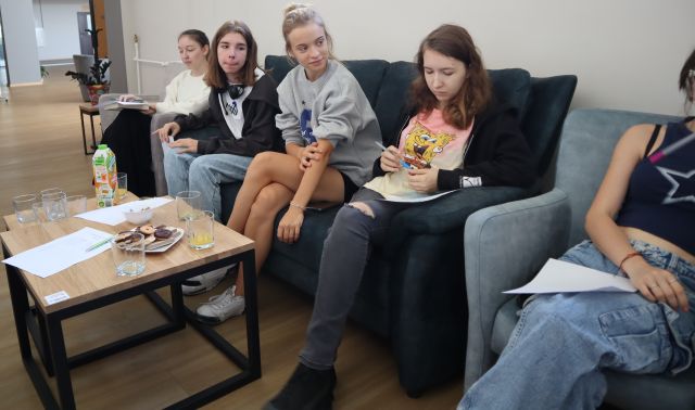 młodzież siedzi na fotelach i sofie