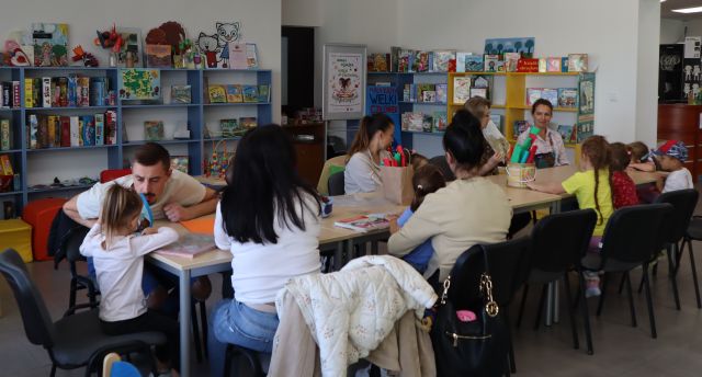 mali i duzi uczestnicy warsztatów siedzą przy stołach