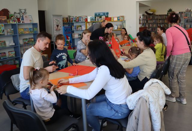 mali i duzi uczestnicy warsztatów wycinają jabłka z pomarańczowych kartek