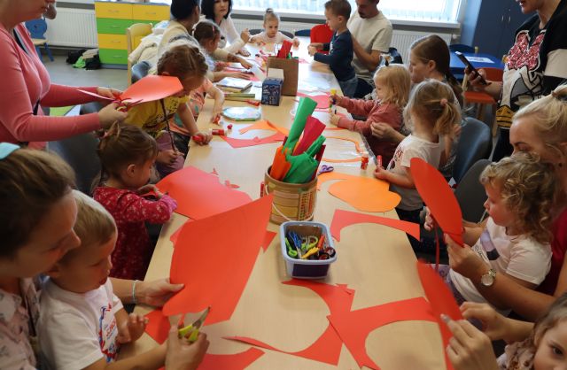 uczestnicy warsztató siedzą przy stołąch z kolorowymi kartkami