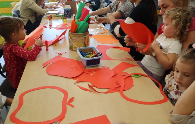 uczestnicy warsztatów wycinają jabłka z pomarańczowych kartek