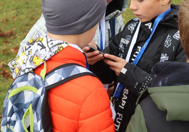 3 chłopców rozwiązuje zagadki gry mibilnej w telefonie