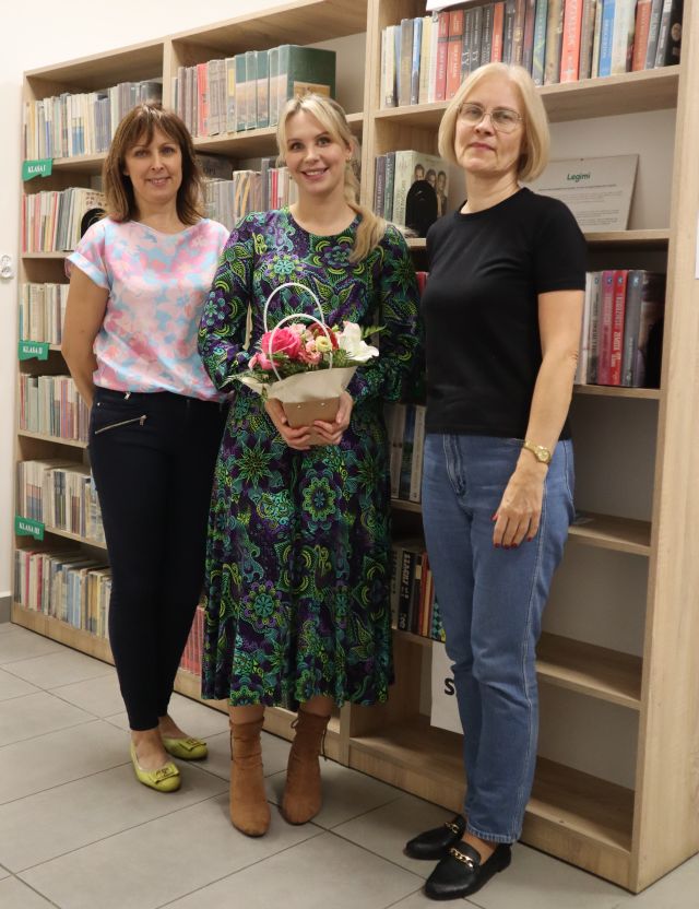 dyrektorka i bibliotekarka pozują do zdjęcia z dziennikarką trzymająca w rękach bukiet kwiatów