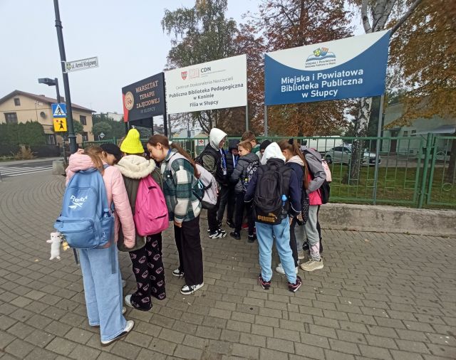 młodzież spaceruje po mieście ze smartfonami rozwiązując zadania gry mobilnej