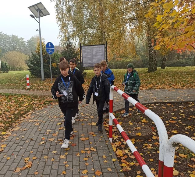młodzież spaceruje po mieście ze smartfonami rozwiązując zadania gry mobilnej