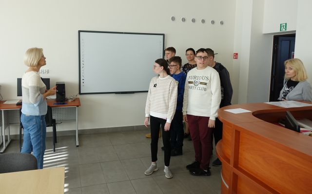 młodzież w asyście bibliotekarki zwiedzają salę komputerową