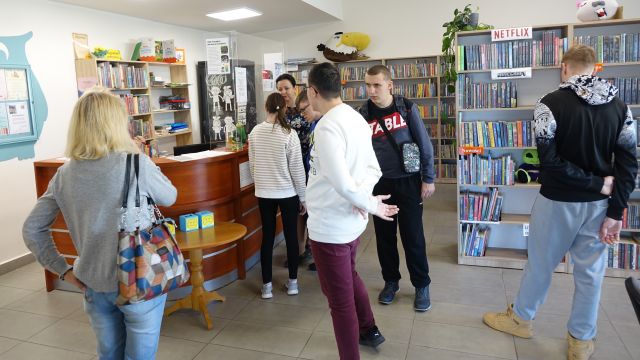 młodzież i bibliotekarka w pomieszczeniu bibliotecznym
