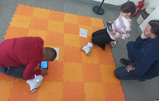 2 dzieci i mężczyzna sterują robotami Photon