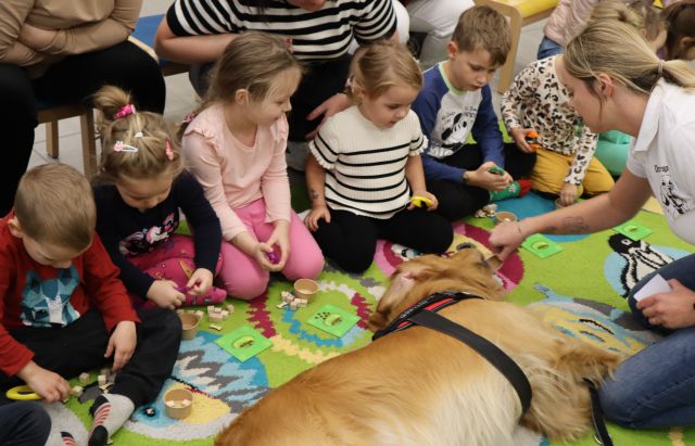na dywanie leży pies, dzieci siedzą i rozwiązują zadania