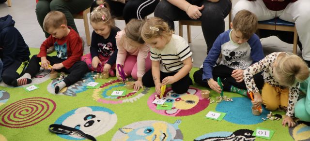 dzieci rozwiązują zadania siedząc na dywanie