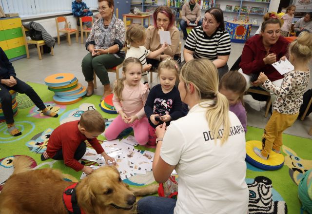 dzieci i terapeutka siedzą z psem na dywanie