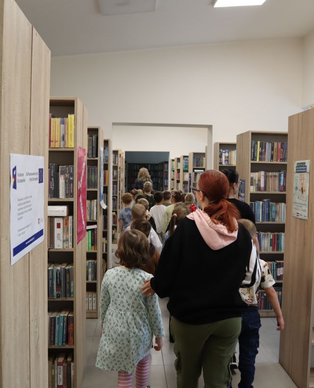 przedszkolaki spacerujące między regałami z książkami